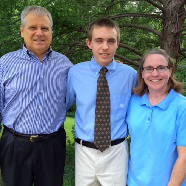 Jim posa para foto ao lado da esposa e do filho no dia da formatura dele