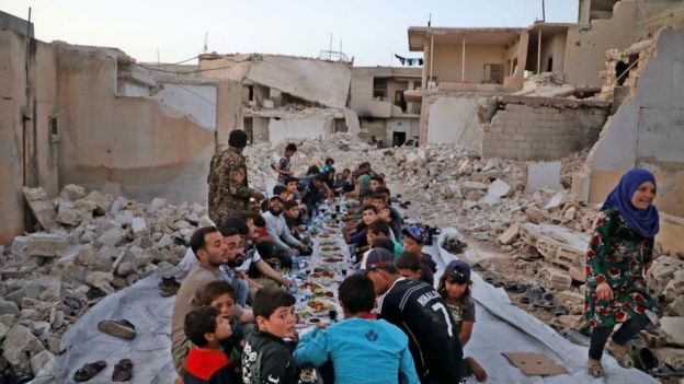 Un grupo de menores come en una zona de ruinas en Siria