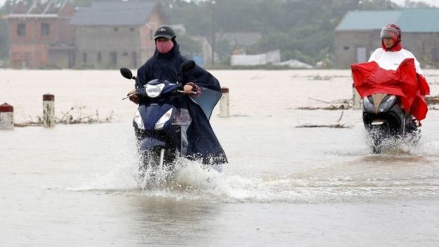 People on scooters ride through flood water in Hue city, Vietnam (05 November 2017)