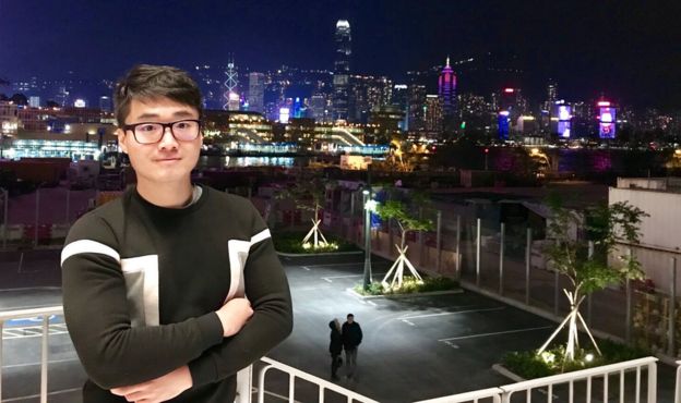 Simon Cheng stands against a city backdrop at night