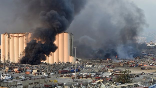 Beirut's destroyed port with smoke rising