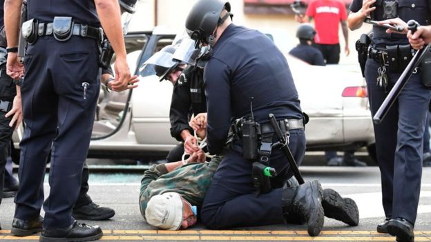 A man is arrested by Los Angeles police officers for violating curfew in Hollywood