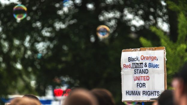 Cartaz em protesto nos EUA pede união de pessoas com origens étnicas diferentes na defesa dos direitos humanos