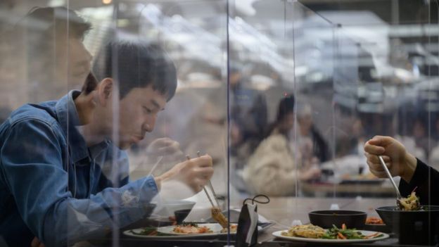 Employees sit behind protective screens, as they eat in a cafeteria at the offices of Hyundai
