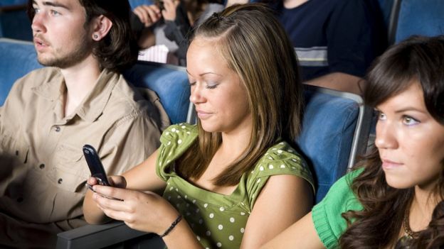 Woman using her phone in a cinema