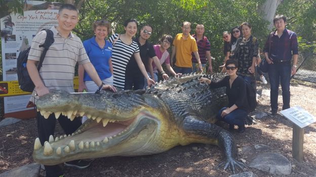 Tourists post with a statue of Ron