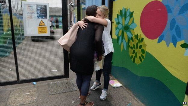 Staff members embrace as the Kids Company closes its building in Camberwell, London.