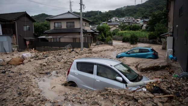 Des vÃ©hicules pris au piÃ¨ge de la boue dans une rue de Saka, prÃ©fecture d'Hiroshima.