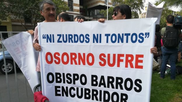 Protesters hold up a sign reading "Neither lefties nor stupid, Osorno is suffering, Bishop Barros [guilty of] cover-up
