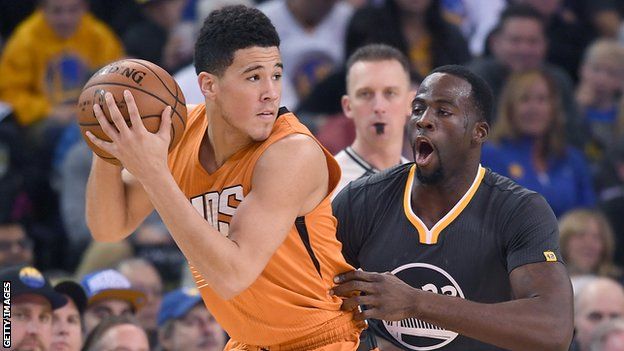 Phoenix Sun' Devin Booker (left) is guarded by Golden State Warriors' Draymond Green during an NBA game