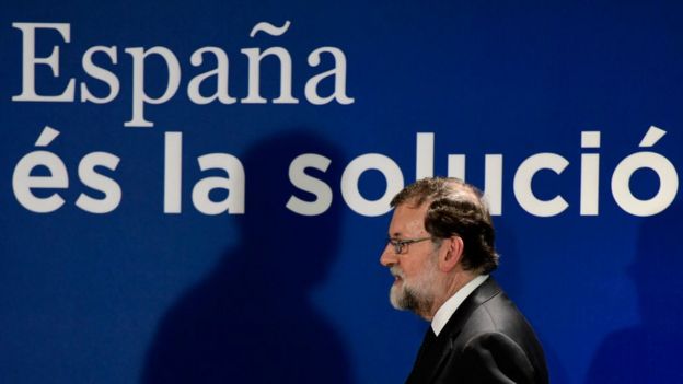 Rajoy caminando tras un letrero que dice 