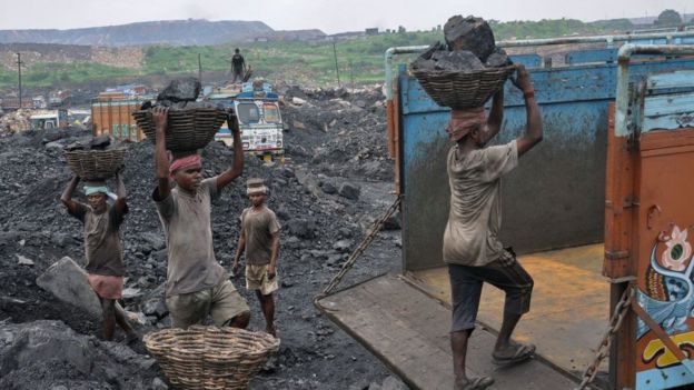 This photo taken on December 7, 2017 shows Indian labourers loading coal onto trucks at an open mine in Dhanbad in the eastern Indian state of Jharkhand.