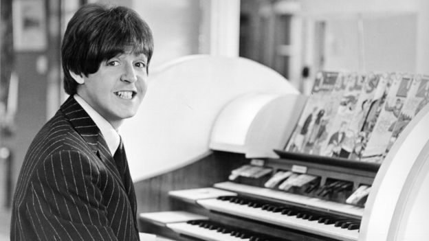 McCartney sonriendo sentado al piano.