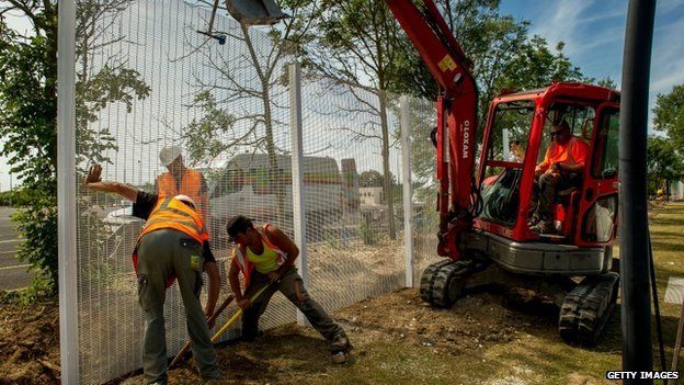 Workers build a fence to protect the Eurotunnel site from migrants who attempt to reach UK by the channel tunnel, in Coquelles near Calais