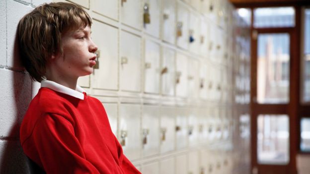 Boy sitting by school lockers