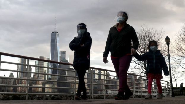 Three people walk with protective coverings in New York