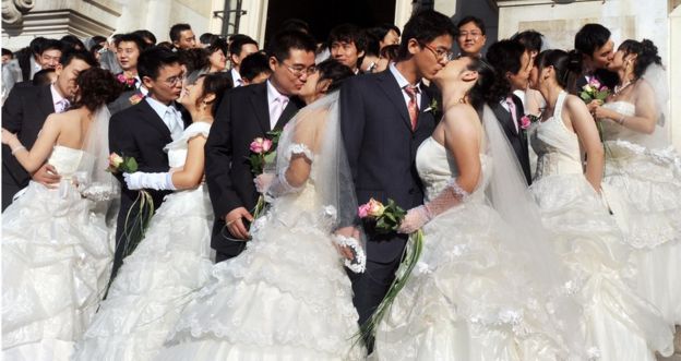 Newly-wed young Chinese couples kiss in front of the Tours city hall, in France Loire's Valley on October 10, 2008, after a wedding ceremony celebrated by the city's mayor.