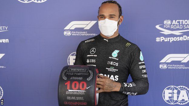 Lewis Hamilton holds up his 100th pole position tyre