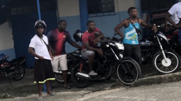 Un grupo de motoratones observa desde el lado de una calle en Buenaventura