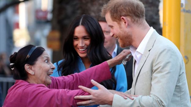 A wide-eyed woman reaches out to Prince Harry