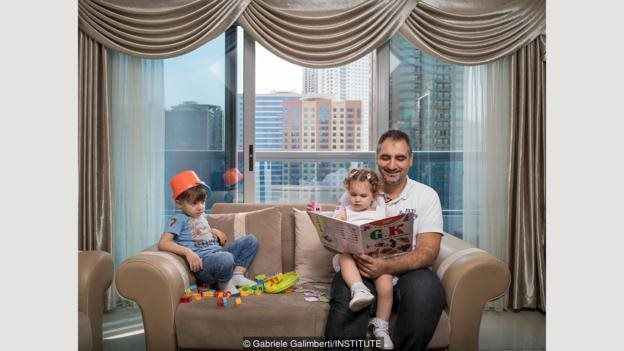 Fouad Kuyali membaca untuk anaknya, Mazen dan Julie, di rumah mereka di Dubai, setelah mereka pindah dari Aleppo, Suriah.
