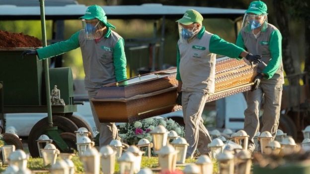 Coveiros levam caixão em cemitério de Brasília