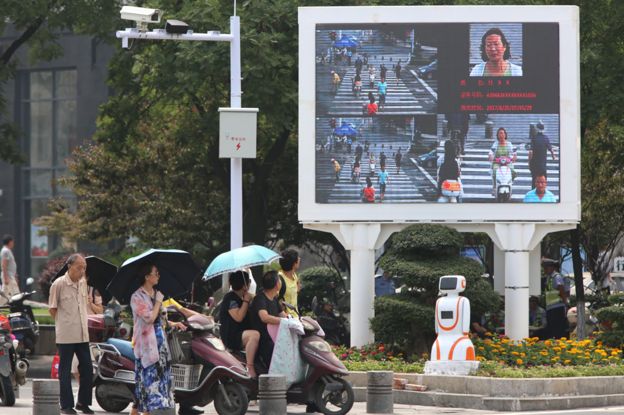 Equipo de reconocimiento facial y una pantalla diseñada para avergonzar a los jaywalkers en una concurrida intersección en Xiangyang el 26 de junio de 2017