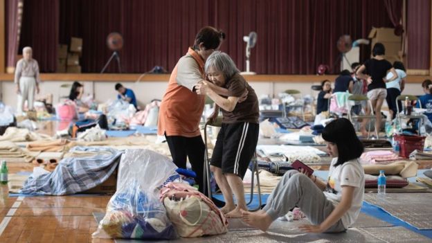 Una anciana (C) es atendida como personas afectadas por las recientes inundaciones en un refugio improvisado en Mabi, prefectura de Okayama el 11 de julio de 2018.