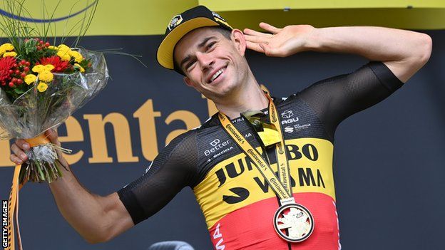 Wout van Aert cups his hand round his ear as he takes in the applause of the crowd on the podium after winning stage 11 of the 2021 Tour de France