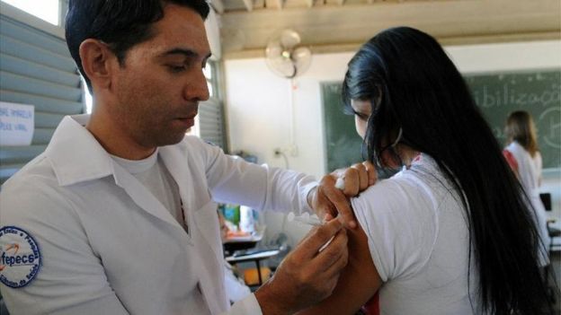 Professora recebendo vacina contra sarampo