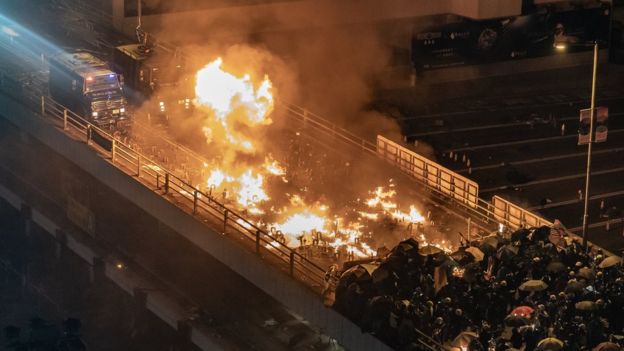 A police personnel vehicle is on fire as protesters and police clash on a bridge at The Hong Kong Poytechnic University on November 17, 2019 in Hong Kong, China.