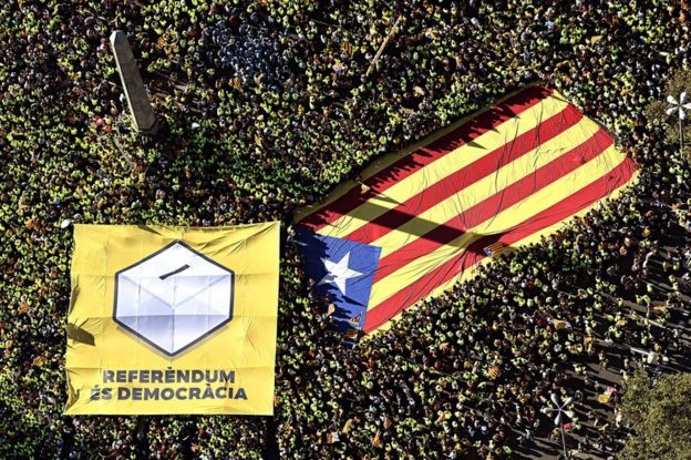 Thousands of people carry a giant Catalan separatist flag and a banner reading Referendum is Democracy in Barcelona, 11 September