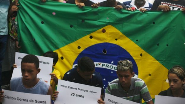 Bandeira do Brasil com buracos para representar tiros de 111 balas disparadas contra 5 jovens no Rio, em 2015