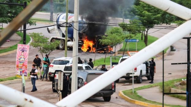 Cartel gunmen are seen near a burning truck during clashes with federal forces