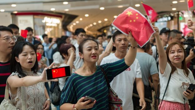 有持中国国旗的人不满示威者在商场聚集。