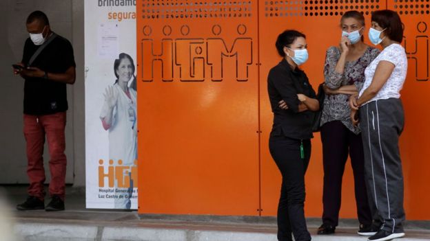 Personas con mascarillas en las afueras de un hospital en Medellín.