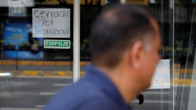 A sign on a business in Caracas reads 'Closed for reconversion' in Spanish