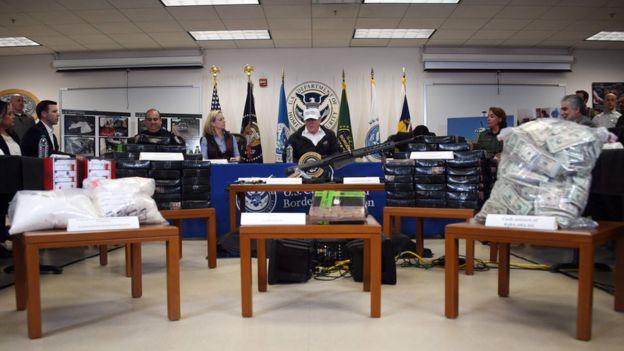 Trump memberikan keterangan di antara tumpukan senjata, uang, dan obat-obatan terlarang yang disita oleh patroli petugas perbatasan AS pada 10 Januari 2019