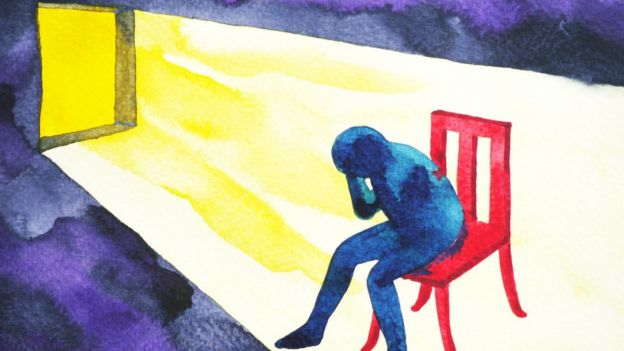 Ilustração mostra boneco dentro de casa sentado, cabisbaixo, protegendo com a mão a cabeça da luz que chega da janela