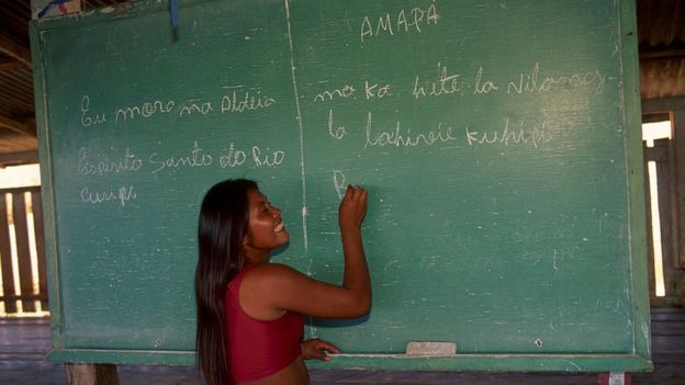 Una mujer indígena escribe sobre una pizarra en Brasil.