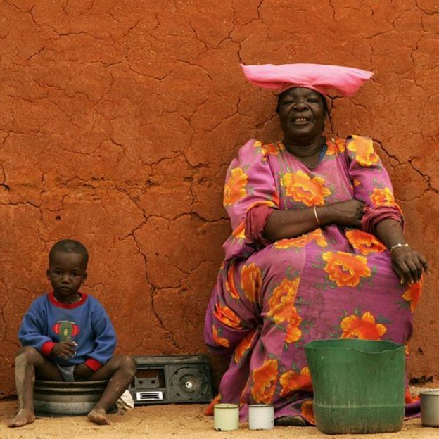Mujer Herero frente a su casa de adobo junto a un niño