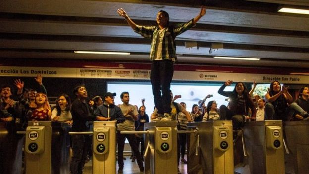 Manifestantes sobre los torniquetes del metro de Santiago de Chile