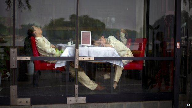 Waiters nap at a table as they wait for customers at a restaurant in Beijing