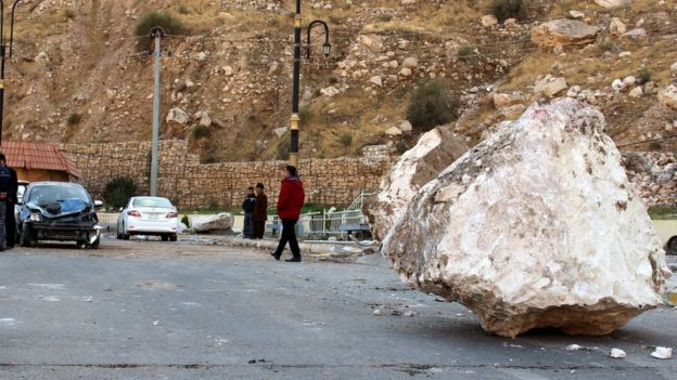 An Iraqi Kurdish man walks by a large rock which fell from the top of a mountain during the earthquake that hit Darbandikhan town
