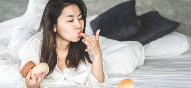 Woman eating doughnuts in bed