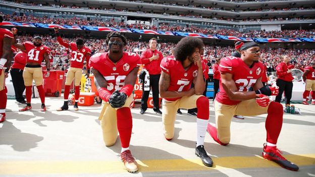 Kaepernick y sus compañeros durante el himno de los Estados Unidos.