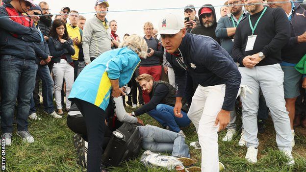 Brooks Koepka attends to the injured woman