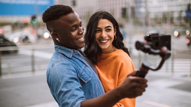 Una pareja sonriendo a una cámara