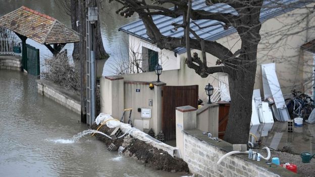 A photo taken on 29 January 2018 shows a barrier erected in front of a house to block floodwater from the Seine river (L) in Bougival, west of Paris