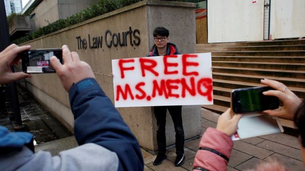 A man holds a sign outside of the bail hearing of Huawei CFO Meng Wanzhou